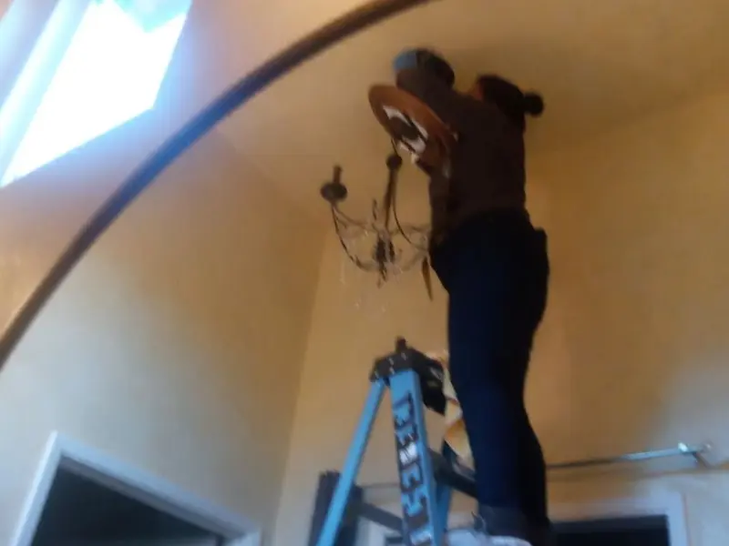 Electrician installing a chandelier in a Lakewood residence